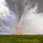 Glowing white tornado with a red dirt cloud around it's base near Lockett, Texas on April 23, 2021.